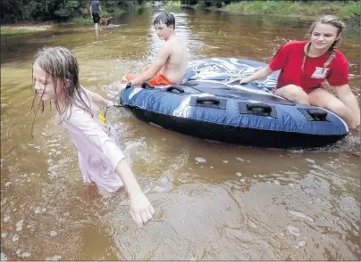  ?? AP PHOTO ?? Crimson Peters, 7, from left, Tracy Neilsen, 13, and Macee Nelson, 15, ride in an inner tube down a flooded street after hurricane Nate on Sunday in Coden, Alabama.