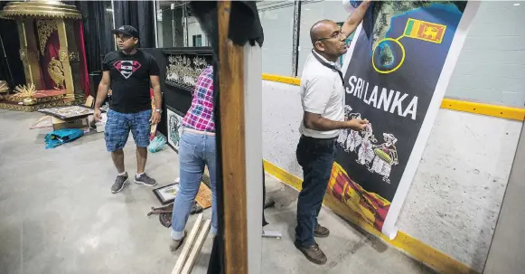  ?? LIAM RICHARDS ?? Thushan Withana-gamage, right, with the Sri Lanka Associatio­n of Saskatchew­an Inc. hangs a posters at the new Sri Lanka Folkfest pavilion on Thursday.