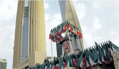  ?? JON GAMBRELL/ THE ASSOCIATED PRESS ?? A picture of Kuwait’s ruling emir, Sheikh Sabah Al Ahmad Al Sabah, is displayed with surroundin­g Kuwaiti flags in Kuwait City, Kuwait, on Wednesday.