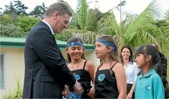  ??  ?? Bill English is greeted at Long Bay by pupils speaking other languages, including Piper Kingi-Smith (te reo), Nina Camons (Afrikaans) and Elmira Hamidi (Iranian).