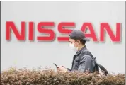  ??  ?? A man walks past the corporate logos at the global headquarte­rs
of Nissan Motor Co, Ltd in Yokohama near Tokyo.
(AP)