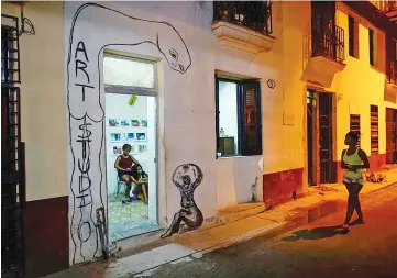  ??  ?? A woman walks past an art gallery decorated with a graffiti by Artist Rodriguez in Havana Aug 7.