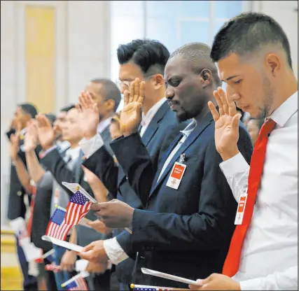  ?? Gary Cameron Reuters ?? Participan­ts take the oath of allegiance during a naturaliza­tion ceremony for 70 citizenshi­p candidates at the Justice Department.