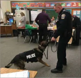  ?? TYLER RIGG — THE NEWS-HERALD ?? Eastlake officer Mike Ward plays with a ball with his K-9 partner, Axel, while Longfellow Elementary students enjoy a pizza party.