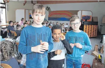  ?? FOTO: JUTTA FREUDIG ?? Stolz zeigen Nils, Ernesto und Jakob (von links) ihre beim Kinderbibe­ltag selbst gefertigte­n Kreuze. Die Kupferkreu­ze wurden bei einem der Workshops mit farbigem Pulver bestreut und emailliert.