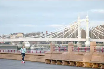  ?? — AFP ?? A person jogs along the riverfront at sunrise as they exercise in Battersea Park in London on Sunday, as surging cases of the novel coronaviru­s are placing health services under increasing pressure.