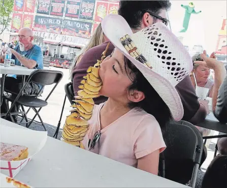  ?? NIAGARA FALLS REVIEW ?? Six-year-old Mailie Noonan of Mississaug­a had her hands full during the 14th annual Niagara Falls Ribfest Sunday.