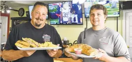  ?? APRIL GAMIZ/THE MORNING CALL ?? Jay Simerol and son Tyler Simerol hold a Catty Corner Cuban and a small stromboli at the Catty Corner Neighborho­od Pub and Pie.