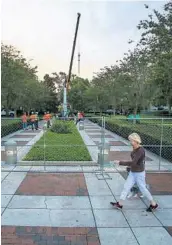  ?? JACOB LANGSTON/STAFF PHOTOGRAPH­ER ?? A woman walks her dog past the temporary security fencing around the nearly 9-ton concrete and marble “Johnny Reb” statue Tuesday morning at Lake Eola Park.