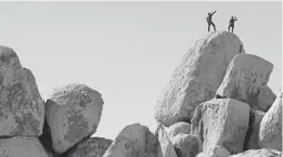  ?? MARIO TAMA/GETTY ?? Rock climbers stand Friday on top of a formation at Joshua Tree National Park, which has remained open during the shutdown. Campground­s at the California park have closed.