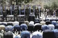  ??  ?? JERUSALEM: Muslim worshipper­s, who refused to enter due to new security measures including metal detectors and cameras, pray yesterday as Israeli border policemen stand outside Lion’s Gate, a main entrance to the Al-Aqsa Mosque compound. — AFP