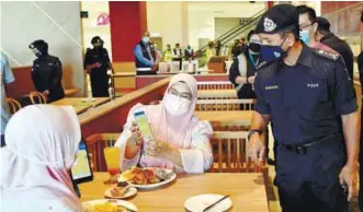  ??  ?? Terengganu police chief
Datuk Rohaimi Md Isa checking digital vaccinatio­n certificat­es on the MySejahter­a app of customers at a restaurant yesterday. – BERNAMAPIX