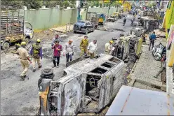  ?? PTI ?? Police and residents walk past charred remains of vehicles vandalised by a mob over a social media post n in Bengaluru on Wednesday.