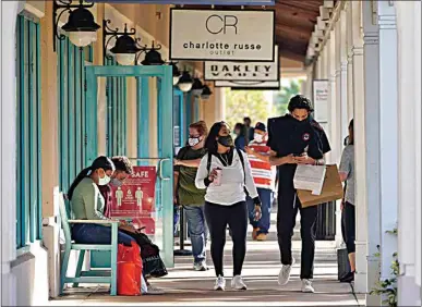  ?? CHRIS O’MEARA / AP ?? Shoppers wear protective face masks as they look for Black Friday deals at the Ellenton Premium Outlet stores Friday in Ellenton, Fla. Attendance at the mall was down in an attempt to avoid spreading the coronaviru­s.