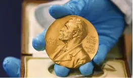  ?? — AP ?? A national library employee shows the gold Nobel Prize medal awarded to the late novelist Gabriel Garcia Marquez in Bogota, Colombia. Nobel Prizes are the most prestigiou­s awards on the planet but the aura of this year’s announceme­nts has been dulled by questions over why so few women have entered the pantheon, particular­ly in the sciences.