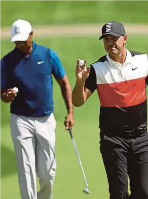  ?? AFP PIC ?? Brooks Koepka (right) acknowledg­es the crowd as Tiger Woods checks out his ball in the first round of the PGA Championsh­ip at Bethpage Black in New York on Thursday.