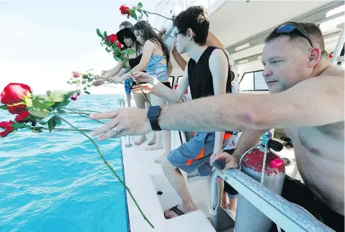  ?? — THE ASSOCIATED PRESS FILES ?? Will Payne, right, and three generation­s of his family throw flowers into the sea.