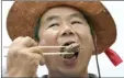  ?? AP photo ?? A member of the Korean Dog Meat Associatio­n chows down during a rally to support the meat Friday in Seoul, South Korea. South Koreans eat dog meat July 12 in the belief it helps them survive summer heat.