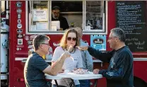  ??  ?? Scott (left) and Barbara Carr, of Greenacres, and Vito Filomeno, of Wellington, sample Wisconsin cheese curds from the Wholesome Rollers food truck in Wellington in October.