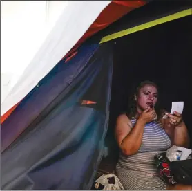  ?? (AP/Gregory Bull)* ?? Morazan applies makeup June 30 inside her tent at a migrant shelter in Tijuana.