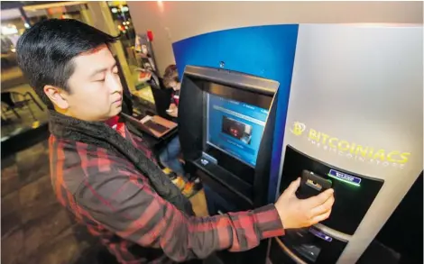  ?? STEVE BOSCH/ PNG ?? Mike Yeung, founder and president of the Simon Fraser Bitcoin club, examines the world’s fi rst Bitcoin ATM in Waves Coff ee House at Howe and Smithe .