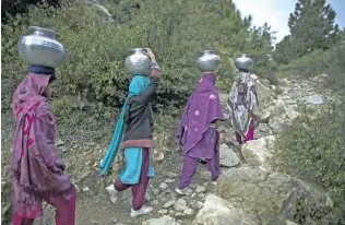  ??  ?? ISLAND OF HEAT: Women carry pots full of water as they walk on Margalla Hills in Islamabad on January 13, 2014. A UN report said in absence of proper planning and developmen­t of effective rainwater drainage systems, urban flooding occurs roughly once...