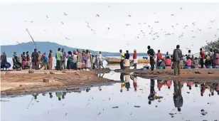  ?? FOTO: DPA ?? Fischhändl­erinnen warten früh am Morgen am Hauptstran­d des Victoriase­e auf Fischer, um ihnen Fisch abzukaufen.