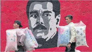  ?? AFP ?? Two salesmen walk in front of some graffiti depicting Venezuelan President Nicolas Maduro in Caracas on Wednesday.