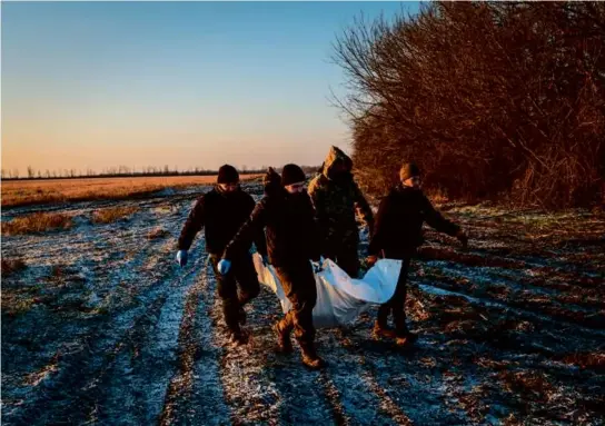  ?? NICOLE TUNG/NEW YORK TIMES ?? Members of a humanitari­an group carried the body of a Russian serviceman in the Donetsk region of Ukraine in January.