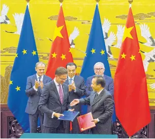  ?? AP ?? Observing from the rear; left to right, European Council president Donald Tusk, Chinese Premier Li Keqiang and European Commission president Jean-Claude Juncker applaud as Chinese and European officials exchange documents at a signing ceremony held in...