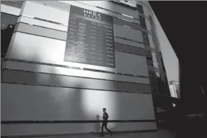  ?? REUTERS ?? A pedestrian walks past a panel displaying securities outside the Hong Kong Exchange.