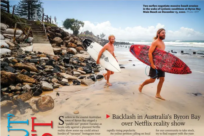  ?? Photo: AFP ?? Two surfers negotiate massive beach erosion in the wake of cyclonic conditions at Byron Bay Main Beach on December 15, 2020.