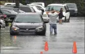  ?? MIKE STOCKER / SOUTH FLORIDA SUN-SENTINEL VIA AP ?? A driver climbs out of his stalled car after he tried to move it to higher ground from a flooded parking lot in Dania Beach, Fla., on Saturday.