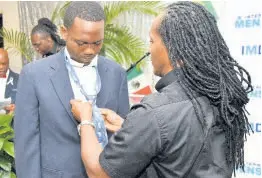  ?? ?? Alando Terrelonge, state minister, Ministry of Culture, Gender, Entertainm­ent and Sport, demonstrat­es to Yarek Hastings the proper way to tie a necktie during Internatio­nal Men’s Day Blazer and Tie edition, under the theme ‘Reigniting a Nation for Greatness: Man Deh Yah’ at The Jamaica Pegasus hotel in New Kingston on Saturday.