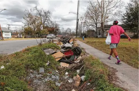  ?? Steve Gonzales / Houston Chronicle ?? A woman walks past a mound of ditch debris in Houston near Collingswo­rth Street and Lockwood Drive on Tuesday. Mayor Sylvester Turner is seeking $10 million toward small emergency drainage repair. Ditches full of debris can cause drainage issue.