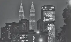  ?? LAI SENG SIN, AP ?? An office building is illuminate­d with “Pray for MH370” next to the Petronas Twin Towers in Kuala Lumpur, Malaysia.