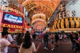  ?? Photograph: Mikayla Whitmore/The Guardian ?? Tourists walk down Fremont Street in Las Vegas. Although the town is back in business after the pandemic, workers are not happy.