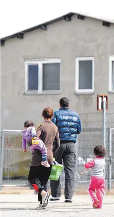  ?? FOTO: DPA ?? Asylbewerb­er vor ihrer Unterkunft: Die Abrechnung der Kosten etwa für Unterkunft und medizinisc­he Versorgung ist zwischen den Landkreise­n und dem Land umstritten. Der Landkreis Ravensburg hat wegen der Ungewisshe­it jetzt eine Haushaltss­perre verhängt.