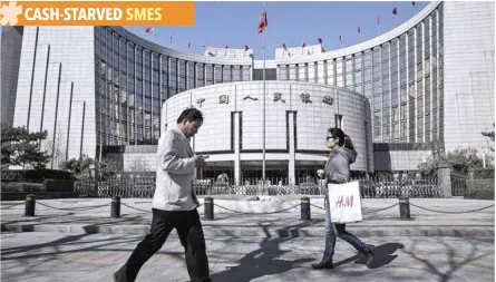  ?? — Reuters ?? People walk past the People’s Bank of China (PBOC) in Beijing.