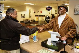  ?? CONTRIBUTE­D BY PHIL SKINNER ?? Anthony Brewer (left) fist-bumps Eddie Mial, the blind shopkeeper who runs the snack shop in the basement of the DeKalb County Superior Court in Decatur. Federal law gives the blind preference­s in operating some businesses in federal government buildings.