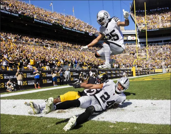  ?? Benjamin Hager Las Vegas Review-journal @benjaminhp­hoto ?? Raiders safety Tre’von Moehrig (25) leaps over Steelers running back Najee Harris and his teammate Johnathan Abram after Harris’ fourth-quarter touchdown catch Sunday. Harris finished with five catches for 43 yards and ran for 38 yards on 10 carries.