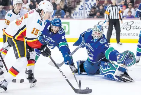  ?? DARRYL DYCK /THE CANADIAN PRESS ?? The Calgary Flames’ Spencer Foo scores against Canucks goalie Thatcher Demko as Jalen Chatfield defends during the first period of a pre-season game at Rogers Arena on Wednesday. Demko allowed three goals in the loss, but didn’t get much help from his defence.