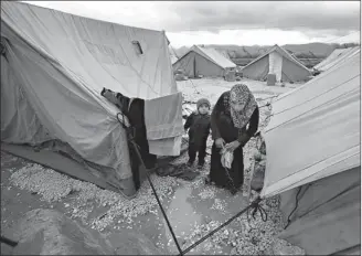  ?? Associated Press ?? In this Jan. 7, 2013, file photo, a Syrian
refugee woman removes her laundry from the ground after it fell at a temporary refugee camp in the
eastern Lebanese town of Marj near the border with Syria.
Internatio­nal aid officials are framing a new...