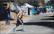  ?? Gary Coronado Los Angeles Times ?? A MAN walks to his tent at a homeless encampment in Anaheim that was cleared late last month.