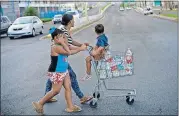  ?? [AP PHOTO] ?? A resident pushes a shopping cart full of recycled bottles filled with water she collected from a water distributi­on center, Thursday in Bayamon, Puerto Rico.