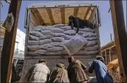  ?? VICTOR J. BLUE/THE NEW YORK TIMES ?? Sacks of flour from a World Food Program convoy are unloaded in Afghanista­n. The Biden administra­tion on Wednesday took steps to ease the pressure that sanctions on the Taliban are having on Afghanista­n.