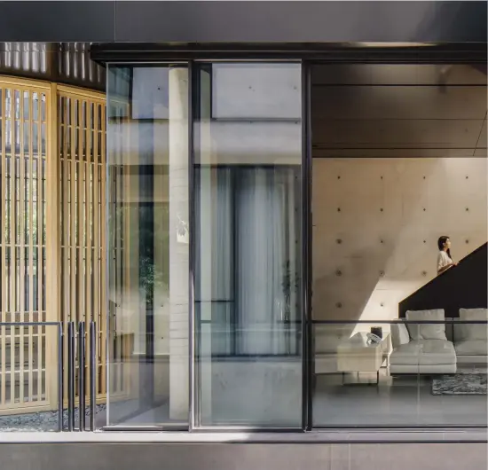  ??  ?? The facade’s concrete appears again as a feature wall in a living space; another feature is the play of light and shadow created by the daylight that pours through a skylight above the cantilever­ed staircase