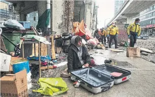  ?? CHRIS YOUNG THE CANADIAN PRESS ?? Police officers move in to help city workers clear an encampment on Bay Street on Friday. The city is providing temporary housing for many homeless instead of shelters during the pandemic.