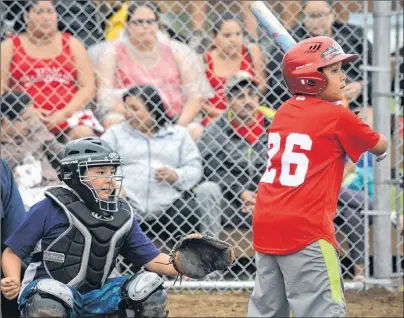  ?? T.J. COLELLO/CAPE BRETON POST ?? Lucas Michael of the We’koqmaq team waits for a pitch in front of Eskasoni catcher Luther Clair during peewee softball semifinal action at the Charlie Peter Googoo Memorial Ballfield in Wagmatcook during last year’s Nova Scotia Mi’kmaw Summer Games. This year’s edition of the Games opens Sunday in Eskasoni.