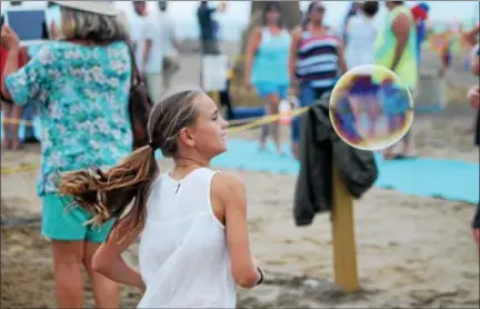  ?? KRISTI GARABRANDT — THE NEWS-HERALD ?? Marissa Lange, 11, Painesvill­es chases bubbles during Beachfest July 22 at Headlands beach.